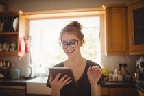Усміхається жінка, використовуючи цифровий планшетний кухні в домашніх умовах — стокове фото