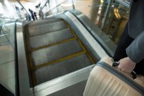 Geschäftsfrau mit Gepäck fährt auf Rolltreppe am Flughafen-Terminal nach unten — Stockfoto