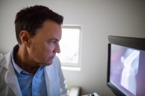 Médico examinando rayos X en computadora personal en el hospital - foto de stock