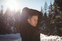 Продуманий чоловік розтягує руки в лісі взимку — стокове фото