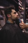 Homem recebendo barba raspada com aparador na barbearia — Fotografia de Stock