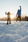 Visão traseira do casal pulando na paisagem nevada — Fotografia de Stock