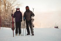 Coppia di sciatori con cielo in piedi sul paesaggio innevato nella stazione sciistica — Foto stock