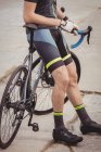 Baixa seção de atleta de pé com bicicleta — Fotografia de Stock
