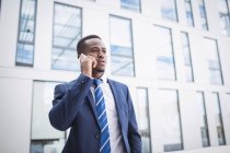Бизнесмен разговаривает по мобильному телефону возле офисного здания — стоковое фото