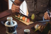 Средняя секция человека с суши в ресторане — стоковое фото