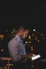 Mann nutzt nachts digitales Tablet auf dem Balkon — Stockfoto