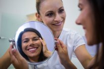 Glückliche Frau überprüft Haut im Spiegel nach kosmetischer Behandlung — Stockfoto