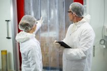 I tecnici discutono mentre tengono tablet digitale in fabbrica di carne — Foto stock