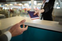 Реєстратор авіакомпанії, який надає паспорт комісару на стійці в терміналі аеропорту — стокове фото