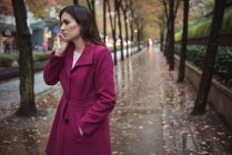 Красива бізнес-леді розмовляє по телефону на мокрій пішохідній доріжці — стокове фото