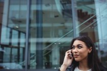 Mulher falando no celular fora do prédio de escritórios — Fotografia de Stock