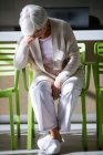 Tensed senior woman sitting on chair in waiting area of hospital — Stock Photo