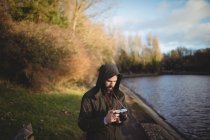 Чоловік дивиться на дисплей на камеру біля берега річки — стокове фото