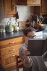 Frau liest Buch in Küche zu Hause — Stockfoto