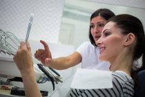 Patientin überprüft ihre Zähne im Spiegel in Zahnklinik — Stockfoto
