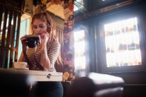 Bella donna controllare le foto in fotocamera digitale al bar — Foto stock
