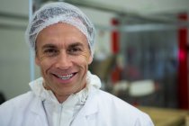 Retrato del carnicero sonriendo en la fábrica de carne - foto de stock