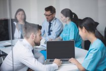 Médicos discutindo sobre laptop em reunião na sala de conferências — Fotografia de Stock