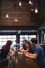 Amigos segurando café no balcão do bar e interagindo com o bartender — Fotografia de Stock