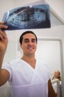 Dentiste regardant plaque de radiographie dentaire à la clinique — Photo de stock