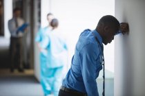 Trauriger Arzt lehnt an Wand im Krankenhausflur — Stockfoto