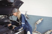 Female mechanic servicing car at repair garage — Stock Photo
