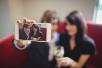 Couple holding drink and taking a selfie in restaurant — Stock Photo