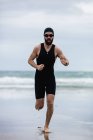 Atleta in costume da bagno correre sulla spiaggia — Foto stock