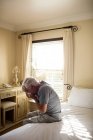 Старший использует салфетку, чтобы высморкаться в спальне дома — стоковое фото