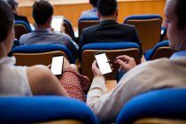 Executivos de empresas que participam de uma reunião de negócios usando telefone celular no centro de conferências — Fotografia de Stock