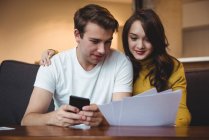 Casal discutindo com documentos financeiros e calculadora na sala de estar em casa — Fotografia de Stock