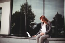 Вагітна бізнес-леді використовує ноутбук в офісних приміщеннях — стокове фото