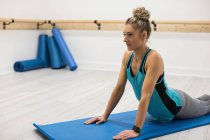 Donna che esegue esercizio di stretching in palestra sul tappeto — Foto stock