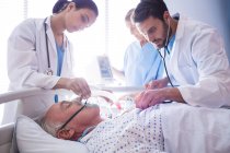 Ärzteteam setzt Sauerstoffmaske auf das Gesicht eines älteren Patienten im Krankenhaus — Stockfoto