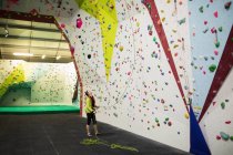 Trainer hält Seil nahe künstlicher Kletterwand in Turnhalle — Stockfoto