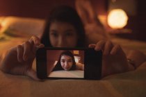 Жінка бере селфі на мобільний телефон у спальні вдома — стокове фото