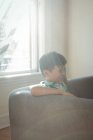 Мальчик сидит на диване в гостиной дома — стоковое фото