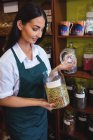 Negoziante femminile che tiene il vaso di spezie in negozio — Foto stock