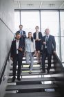 Portrait of confident business people standing on staircase in office — Stock Photo