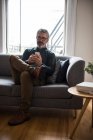 Mann benutzt Handy im heimischen Wohnzimmer — Stockfoto