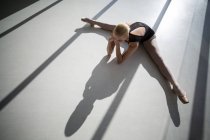 Draufsicht auf die Ballerina, die sich auf dem Boden dehnt — Stockfoto