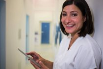 Портрет улыбающегося врача с помощью цифрового планшета в клинике — стоковое фото