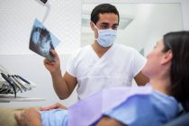 Dentista explicando la radiografía a la paciente femenina en la clínica - foto de stock