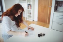 Pregnant woman filling document at home — Stock Photo
