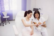 Medico e paziente femminile discutono su tablet digitale in clinica — Foto stock