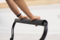 Nahaufnahme weiblicher Hände, die verstellbare Fußstange am Reformer im Fitnessstudio halten — Stockfoto