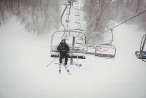 Человек на лыжном подъемнике поднимается на гору — стоковое фото