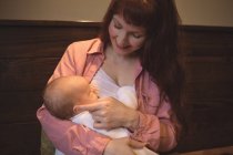 Mother holding cute baby daughter in arms at cafe — Stock Photo