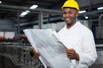 Retrato do trabalhador masculino sorridente lendo instruções na fábrica de suco — Fotografia de Stock